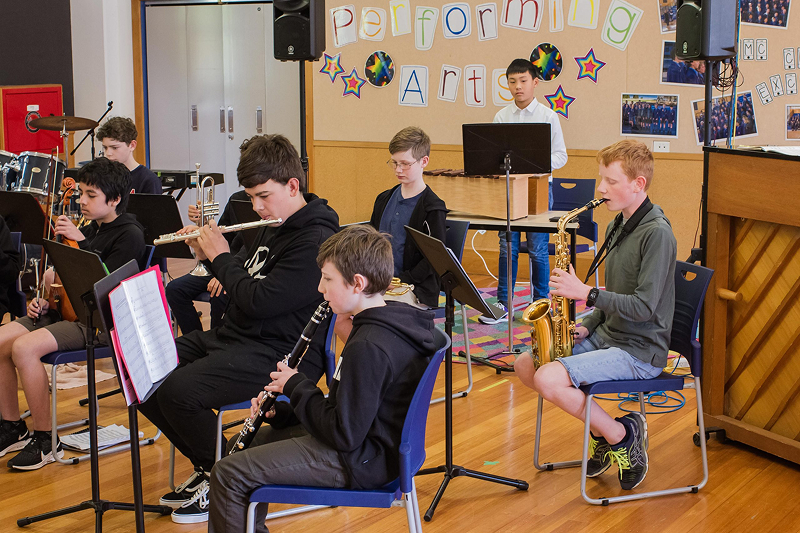 A school band in the Performing Arts room playing flute, saxophone, and keyboard
