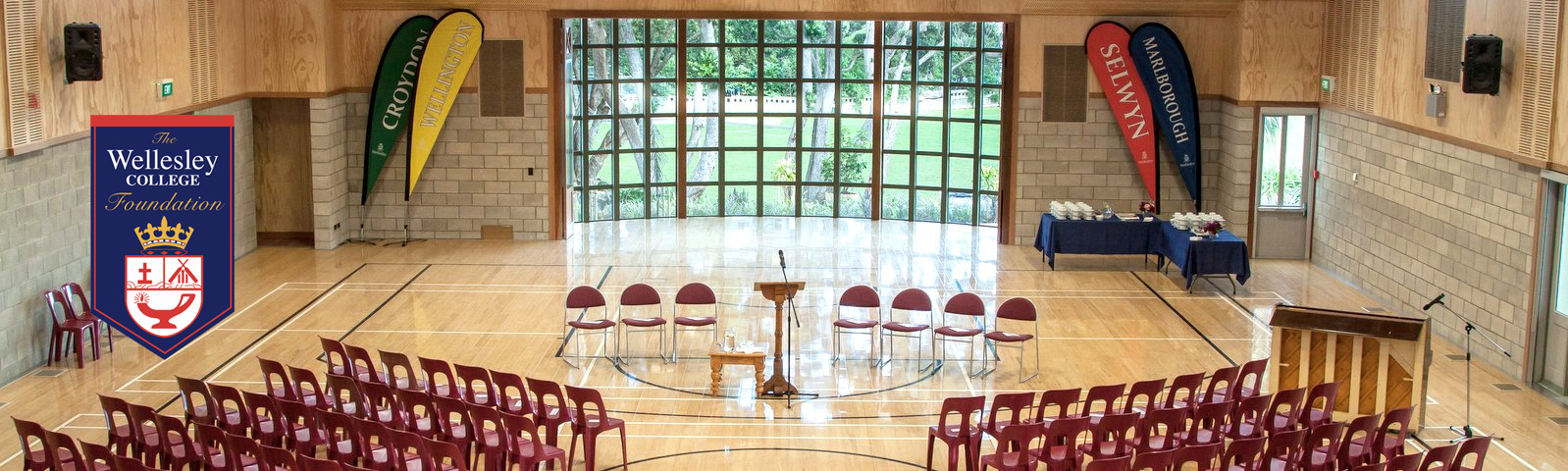 Wellesley College Hall, a large building with windows and a pitched roof, surrounded by greenery