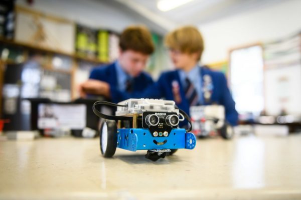 Two students working with a robot in a STEM classroom, with computers and equipments