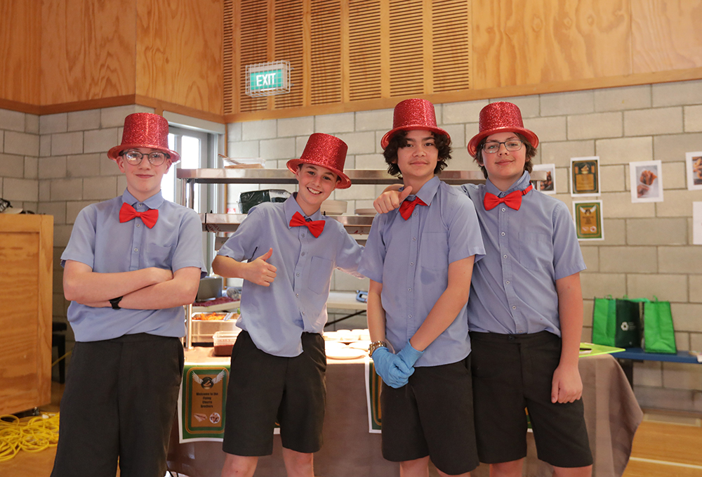 Four boys in Wellesley College uniform smile at the camera
