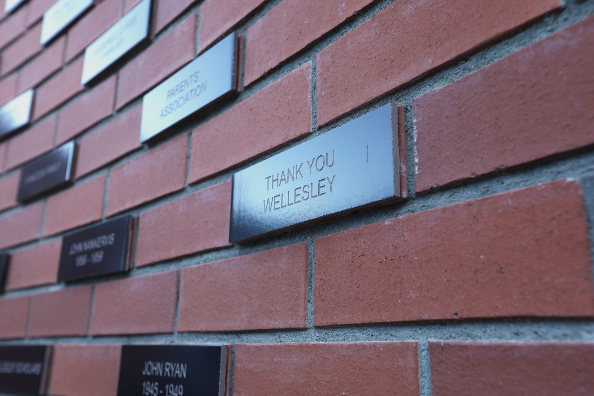 A brick wall with the words “Thank You Wellesley” displayed on it